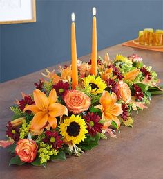 an arrangement of flowers and candles on a table