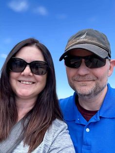 the man and woman are taking a selfie in front of the blue sky with clouds