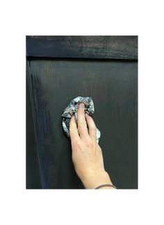 a person wiping up a black door with a rag