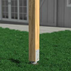 a wooden post in the middle of some grass near a building with doors and windows