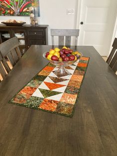 a bowl of fruit on top of a wooden dining room table with matching placemats