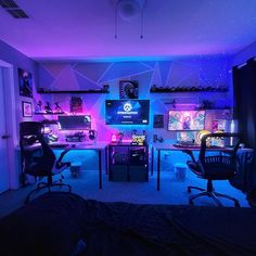 a room with two computer desks and chairs in it, all lit up by neon lights