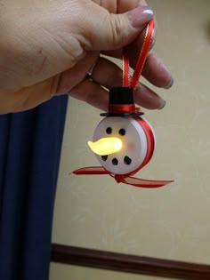 a snowman ornament hanging from a string with a light on it's head