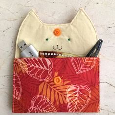 an orange and red pouch with a cat face on it's side, filled with various items