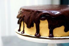 a chocolate and yellow cake on a white plate with icing drizzled