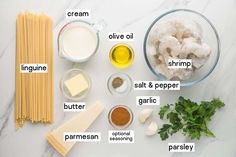 ingredients to make pasta laid out on a white counter top, including parmesan cheese, cream, olive oil, shrimp, salt and pepper