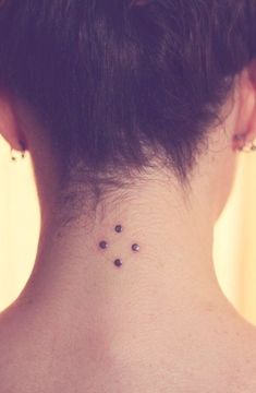 the back of a woman's neck with three small dots on her left side