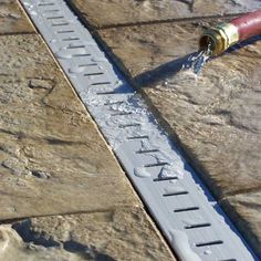 a water hose is connected to the side of a brick wall that reads, drain