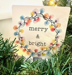 a merry and bright sign hanging from a christmas tree with lights in the background, surrounded by greenery