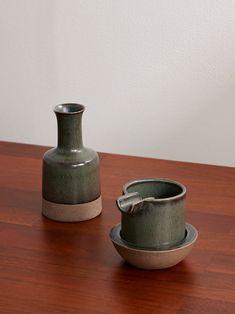 two green vases sitting on top of a wooden table next to eachother