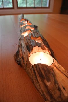 a candle that is sitting on top of a wooden log with some lights in it