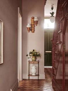 a hallway with pink walls and wooden stairs