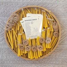 a basket filled with lots of yellow candles next to tags and twine on strings