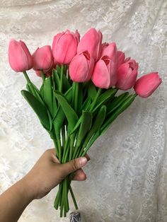 a hand holding a bouquet of pink tulips