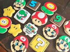 some cookies are decorated with mario and other items on a wooden table, along with the numbers