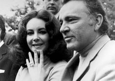 black and white photograph of two people holding their hands up to the camera, with three other people behind them