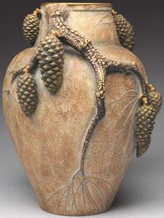 a ceramic vase with two pine cones on it's side and an insect crawling out of the top