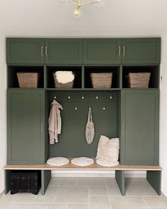 a green bench sitting in front of a wall filled with cabinets and baskets on top of it