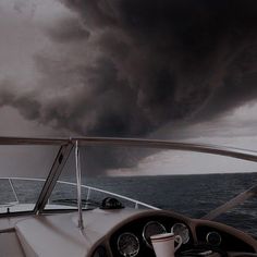 a black and white photo of a storm coming in from the ocean on a boat