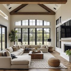 a living room filled with lots of furniture next to a fire place and large windows