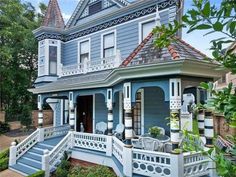 a large blue house with white trim on the front porch and steps leading up to it