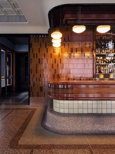 an empty bar with several bottles on the shelves and lights hanging from the ceiling above it