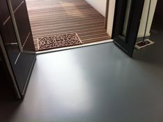 a bathroom with a wooden floor next to a black cabinet and shower stall in the corner