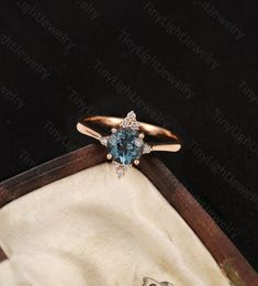 an engagement ring with a blue topazte surrounded by diamonds in a wooden box