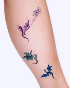 a woman's leg with three different colored dragon tattoos on her left arm and the other side