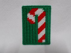 a green and white knitted patch with a candy cane on it's side