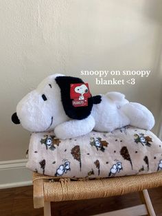 a stuffed snoopy dog laying on top of a blanket that is sitting on a chair