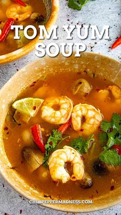 two bowls of tom yum soup with shrimp, peppers and cilantro on the side