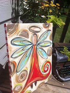 a painting sitting on top of a wooden table next to a planter filled with flowers