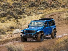 a blue jeep driving down a dirt road