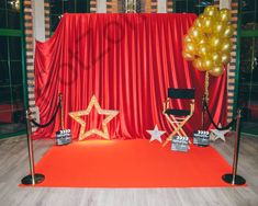 a red carpet with gold stars on it and two golden star balloons in the air