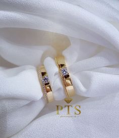 two gold wedding rings with diamonds on white fabric