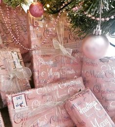 pink wrapped presents under a christmas tree with ornaments