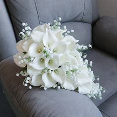 a bouquet of white flowers sitting on top of a gray couch next to a pillow