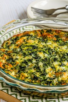 a casserole dish with spinach and carrots in it on a table