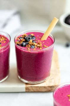 three glasses filled with blueberry smoothie and granola