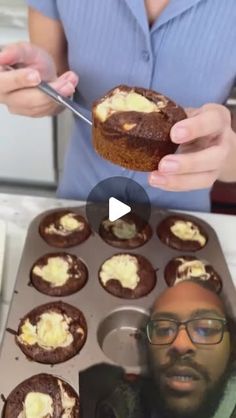 a man holding a cupcake in front of a muffin tin filled with frosting