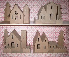 some paper cut out houses sitting on top of a shelf with pink and white wallpaper