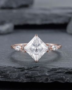 an engagement ring with a princess cut diamond surrounded by three small diamonds on top of it