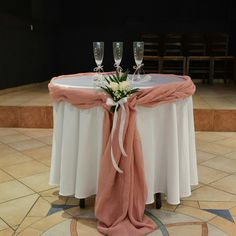 the table is set up with champagne glasses and a pink sash around it for an elegant touch