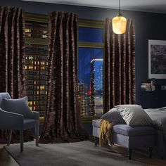 a bedroom with a bed, chair and window overlooking the city at night in front of it