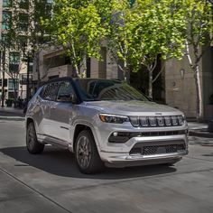 a silver jeep is driving down the street