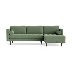 a green sectional couch with wooden legs