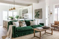 a living room filled with green couches and pillows on top of a wooden table