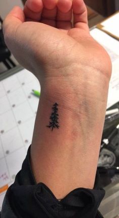 a small pine tree tattoo on the wrist