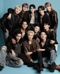 a group of young men sitting next to each other in front of a blue background